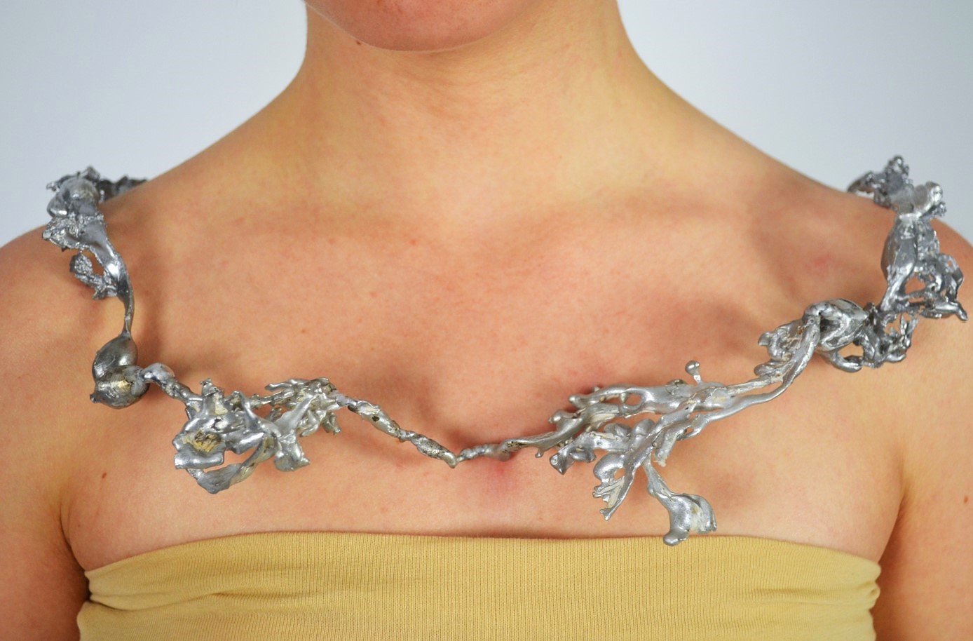 Alluminium casts of bladderwrack seaweed spread cross the chest and lay on the shoulders.