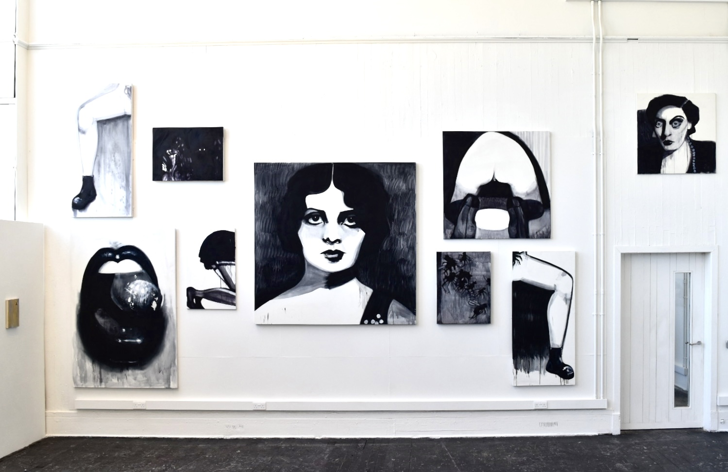 black and white collage of various sized canvases, a large lady in the centre and legs manspreading the whole wall