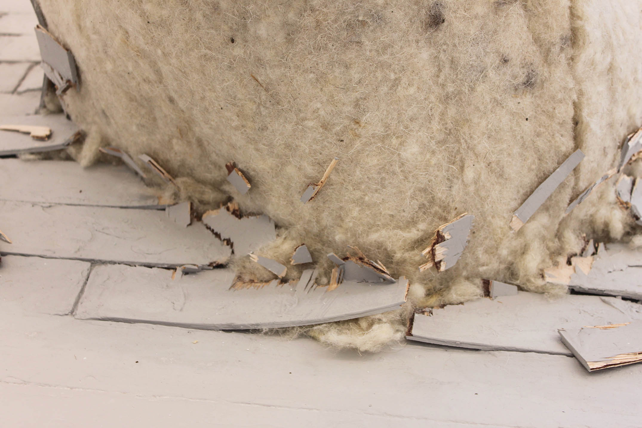 Close-up of a sculpture made from wool insulation bursting through the floorboards.