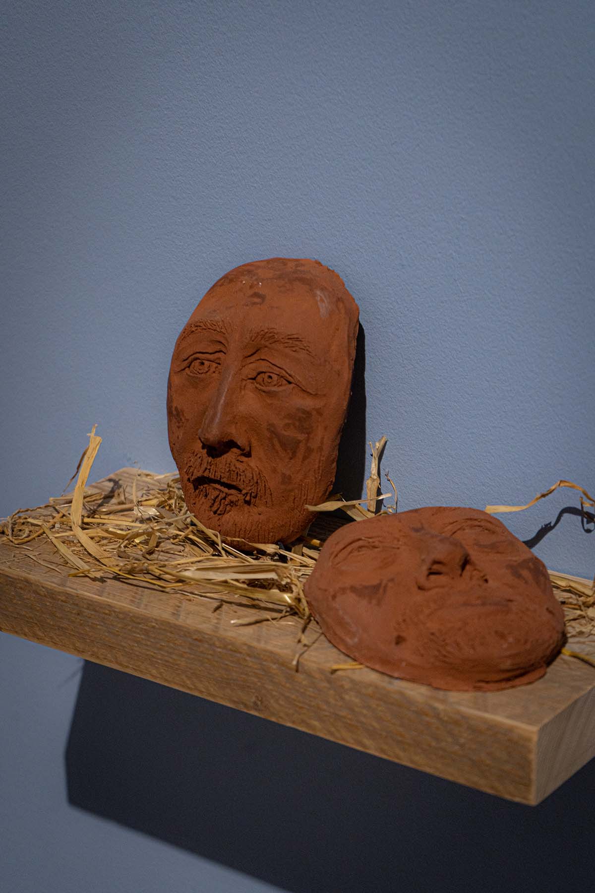 two ceramic faces on a shelf. 
