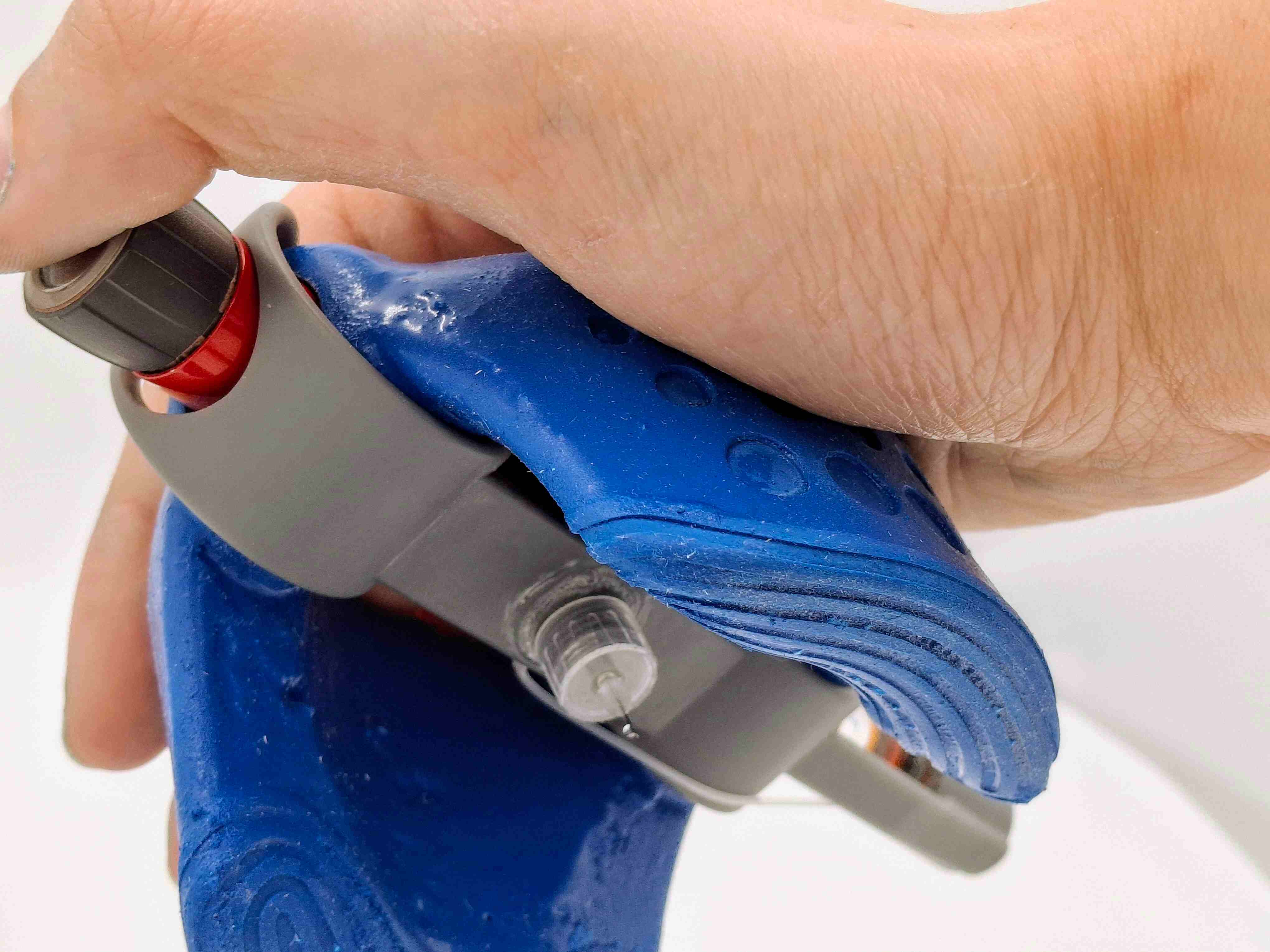 Injector shown from below, where we can see the needle and a hand is holding it whilst pressing the insulin pen's dial, ready to inject.