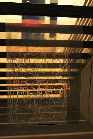 Under-side of stairs case with light shining through it in lines, a transparent piece is hung below it.