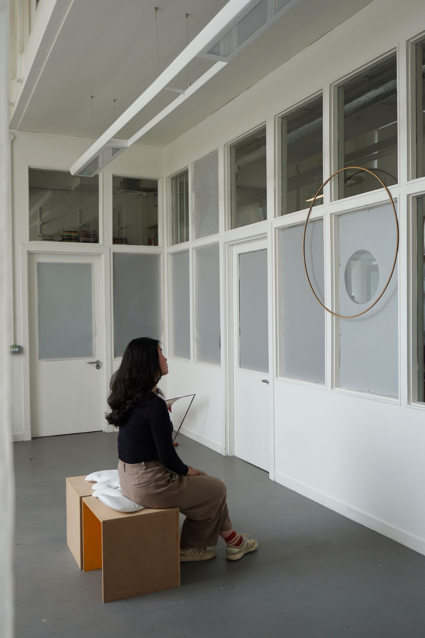A person sitting on the movable stall in front of the installation, 'Letting it sink in', 2025. 