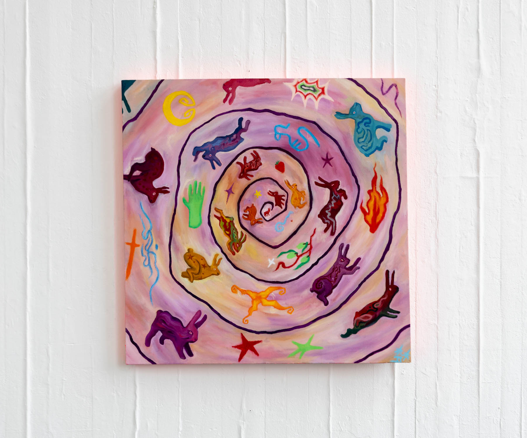 Square painting against a white wall of hares and rabbits running within a spiral. They are multicoloured and in between them are abstract symbols and illustrations. The background is pastel purple and yellow.