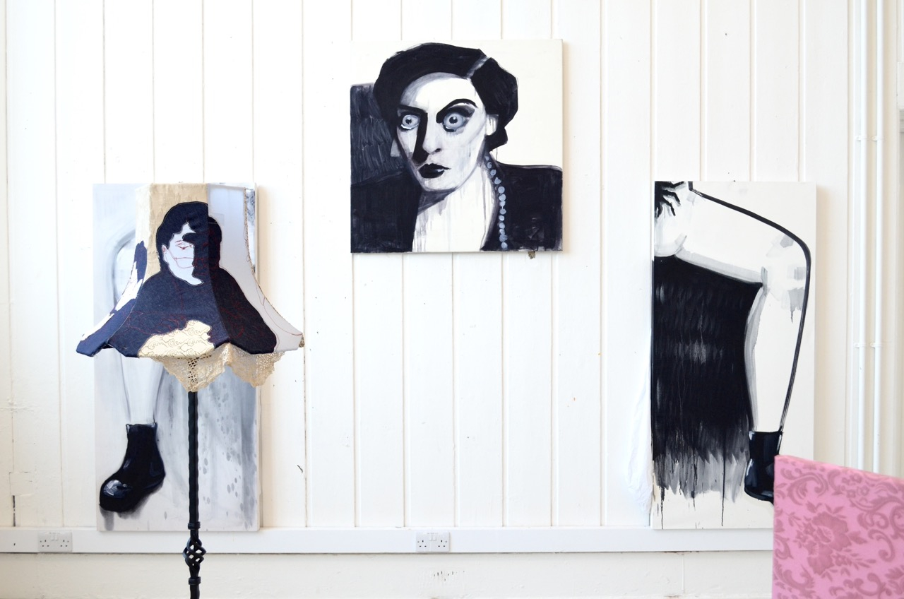 a black and white painting of Joan Crawford with leg paintings manspreading either side of her, with a fabric lamp by another artist censoring the leg on the left 