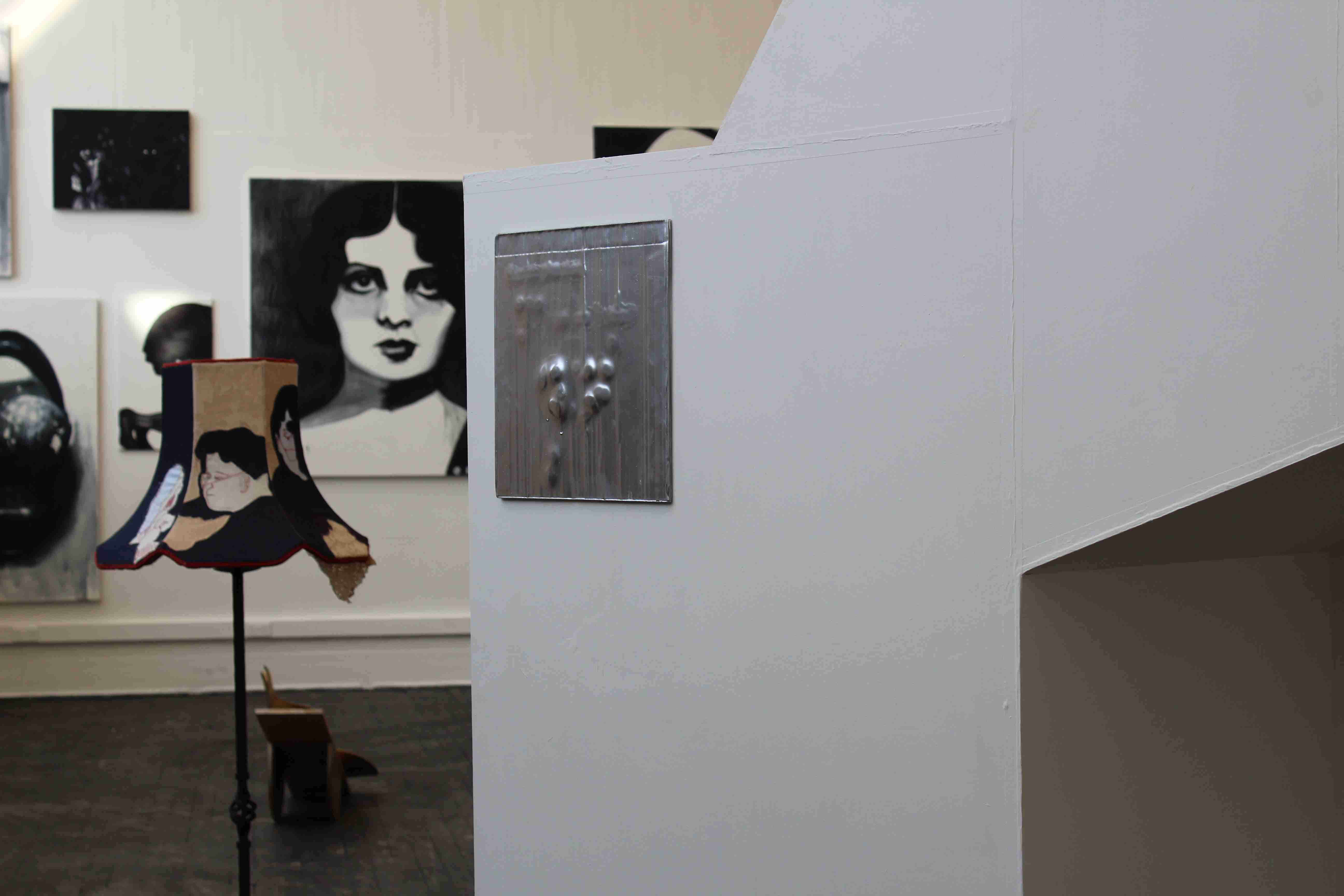 Installation of a small silver painting with other Graduate Show artists work in the background