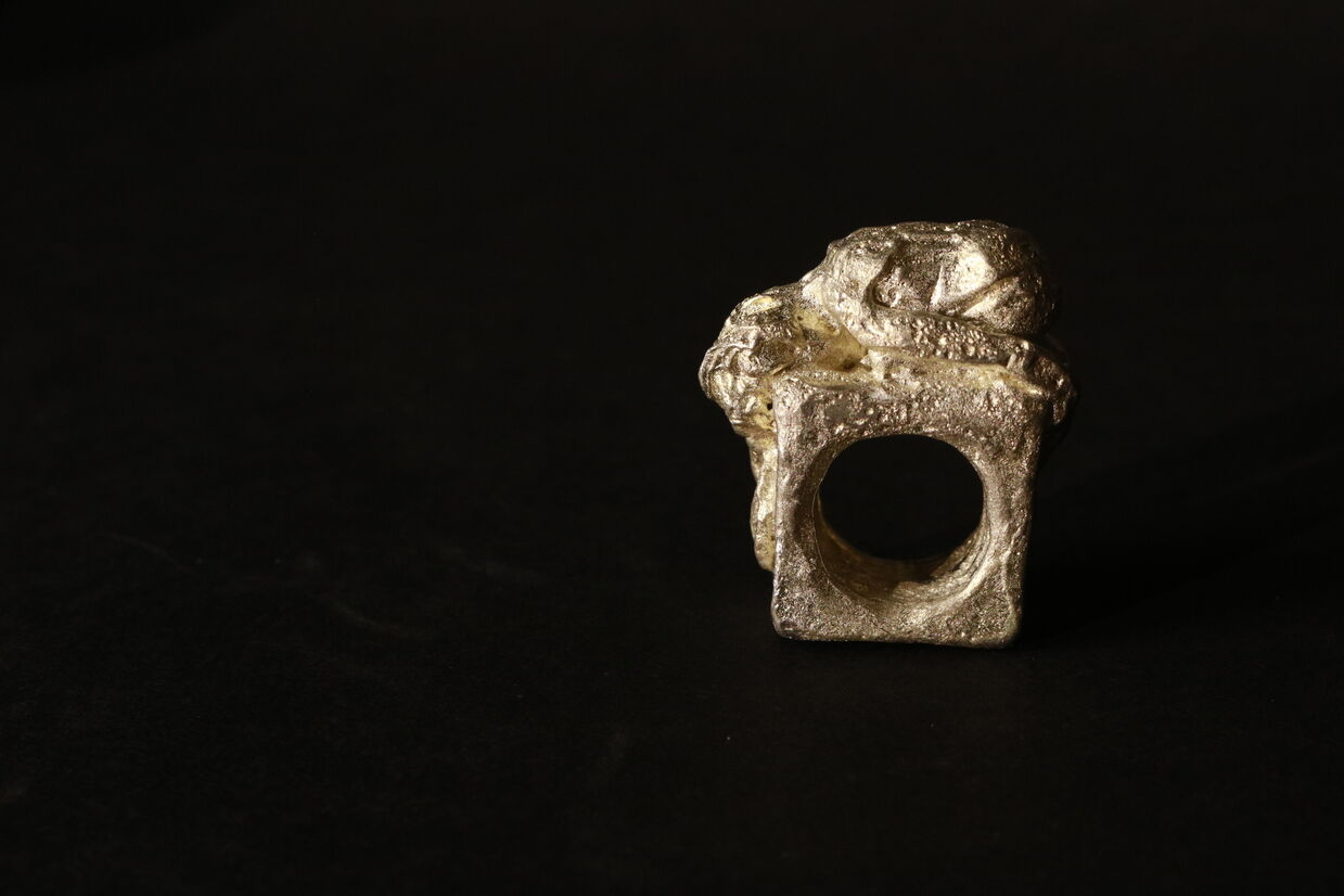 Pewter ring of a woman laying down.