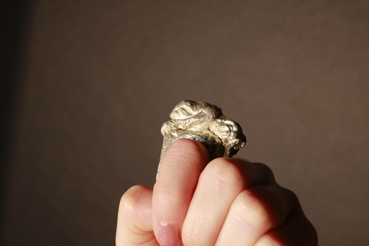 Pewter ring of a woman laying down, worn on a finger.