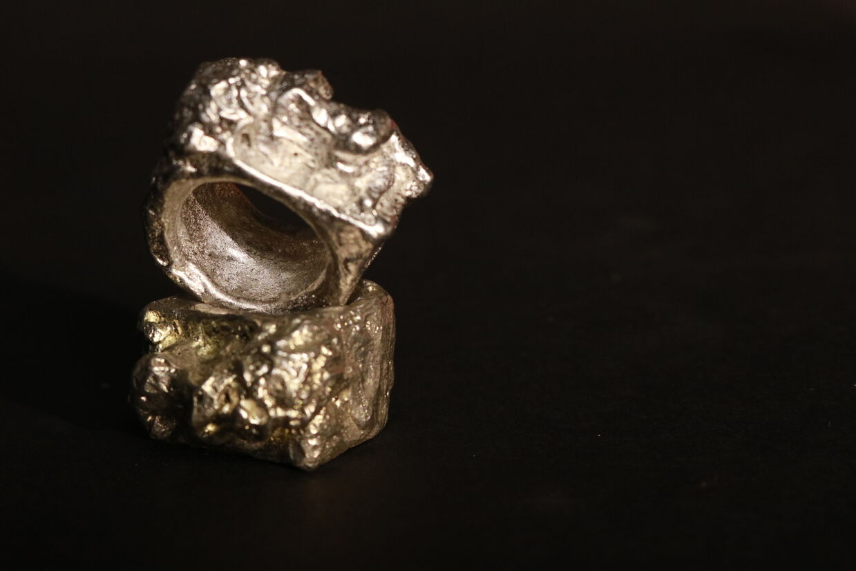 Two pewter rings of women laying down, showing metal variety from silver to green hues.