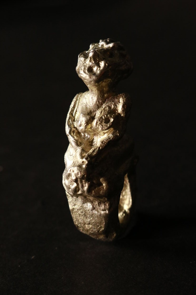 Pewter ring of a woman sitting facing up.