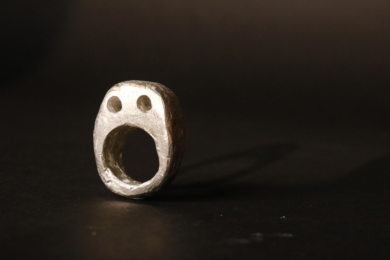 Pewter ring of a brutalist face. 