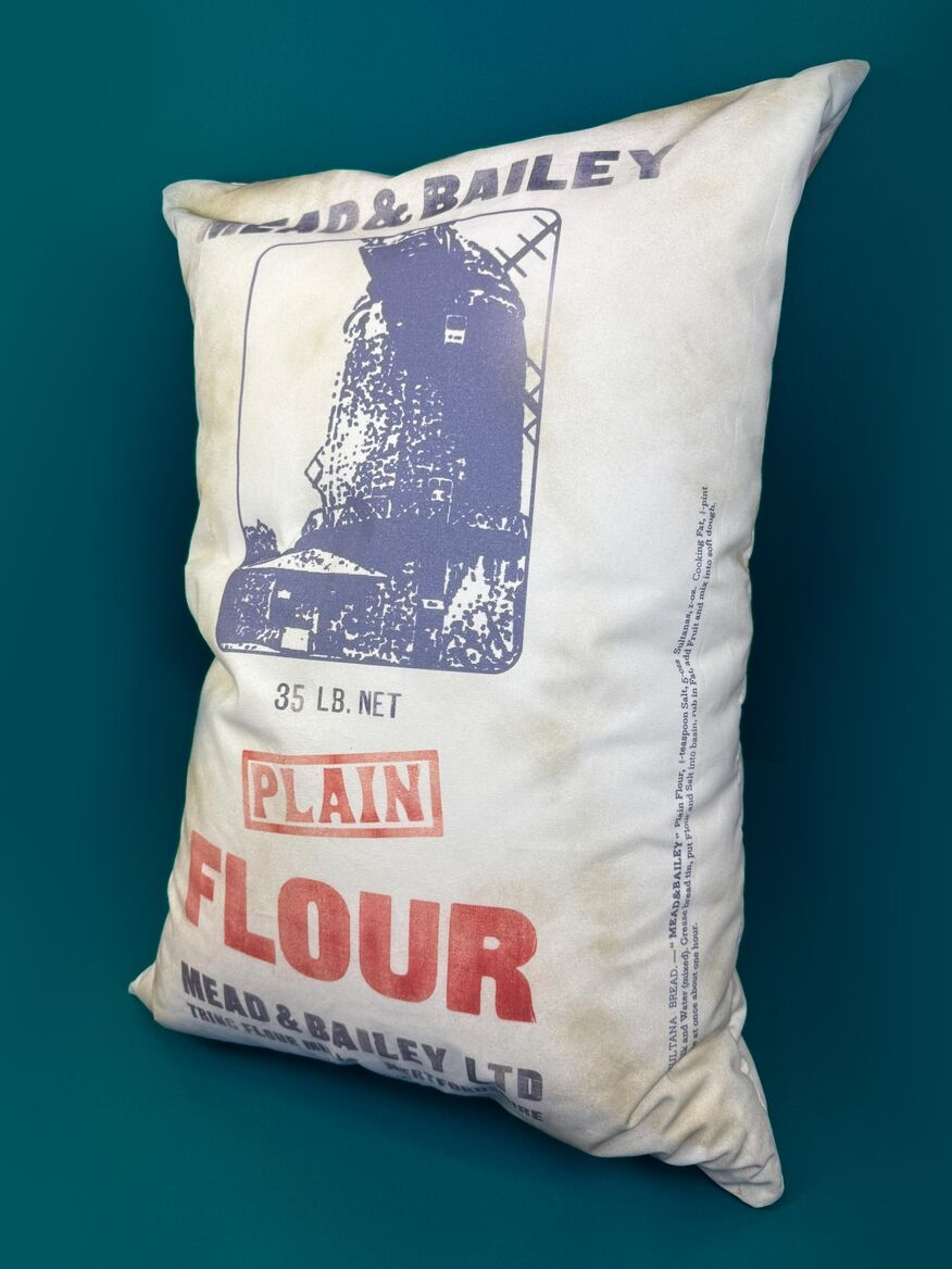 Flour bag displayed at an angle to show hand printed elements such as company logo, product name, weight, flour mill illustration and recipes. Displayed on a deep blue background 