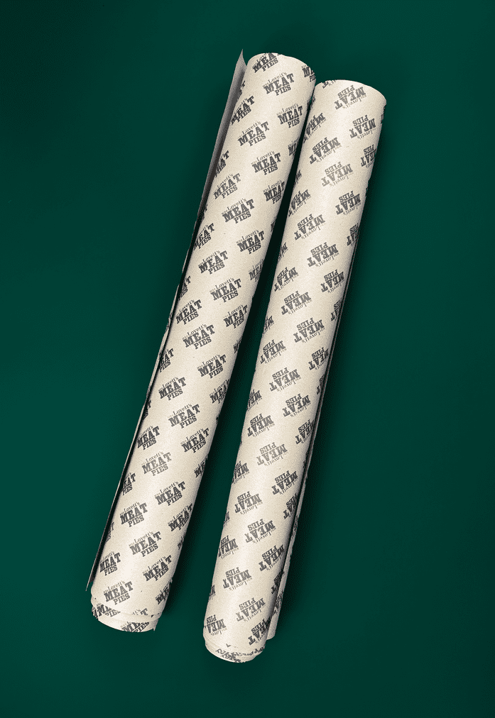 two rolls of kraft paper with repeating print pattern that says 'Mrs Lovett's Meat Pies'. Displayed against a dark green background