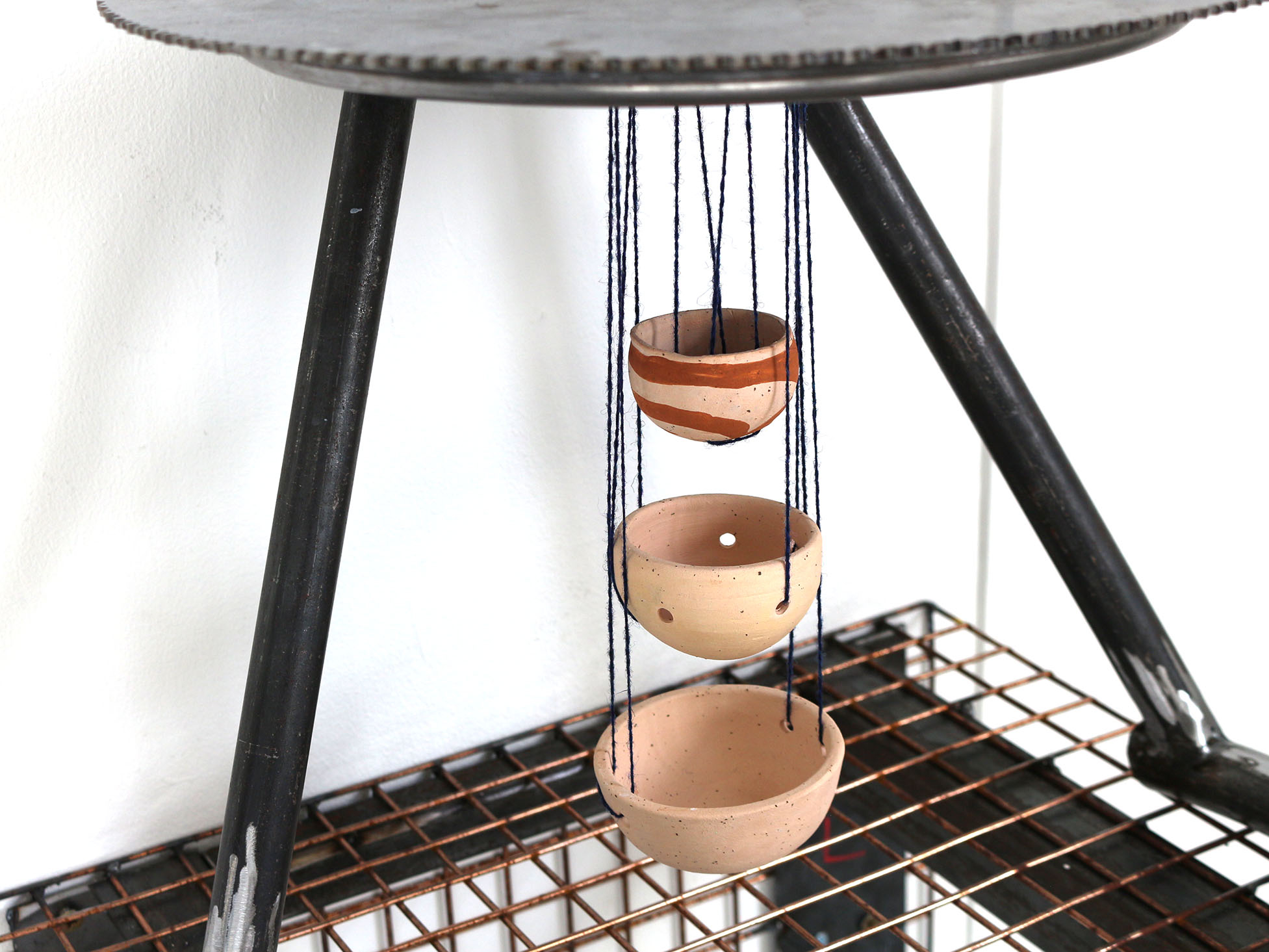 Side view of circular ceramics hanging off a metal sculpture