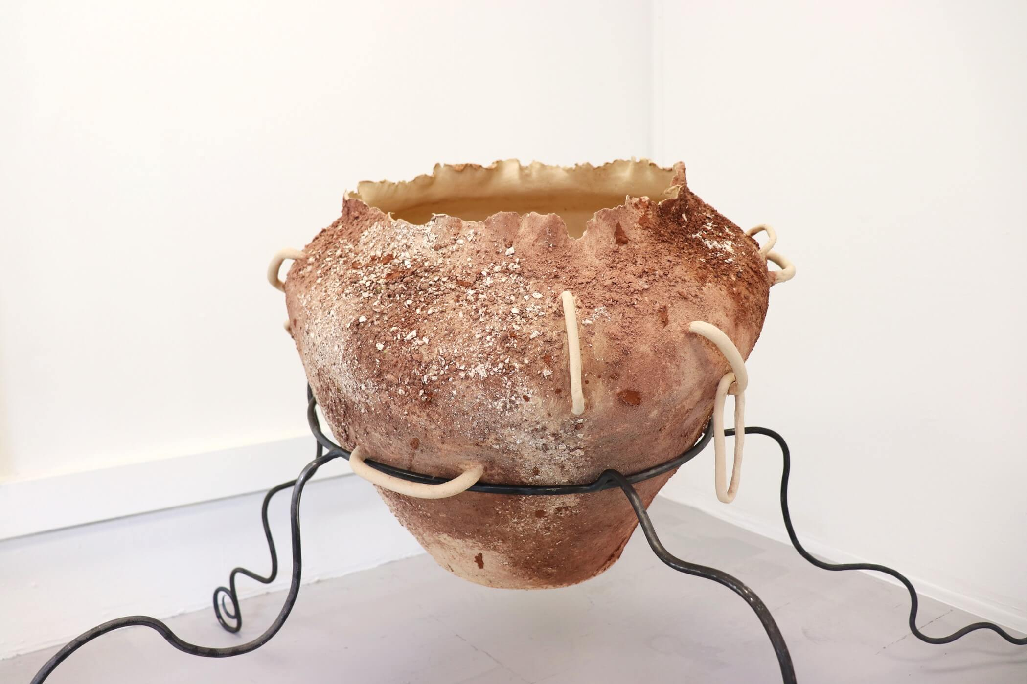 Large ceramic pot embedded with red and cream crushed rocks with several unusual ceramic handles.