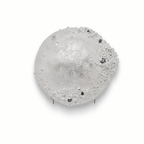 A close up of a silver bead, showing the detail of the ancient technique of granulation.