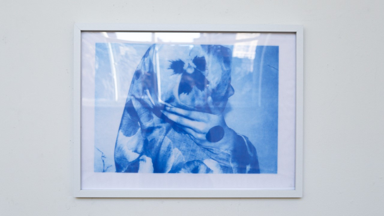 Fabric mesh framed, with figure cradling their head in monochromatic blue colourway