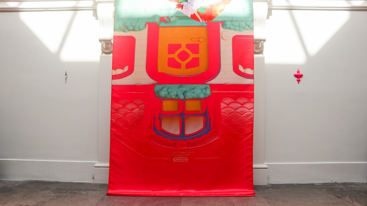 Eye level of the middle banner touching the ground, with the hot pink door knocker on the wall beside the middle banner.