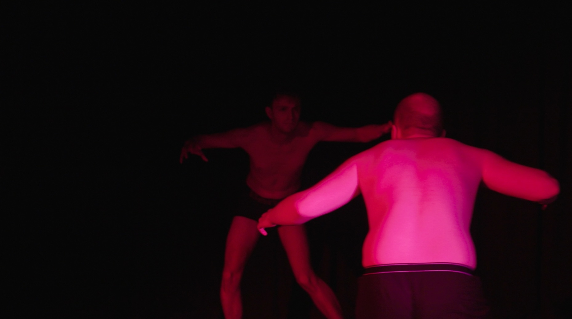 two men in pink lighting with about to attack