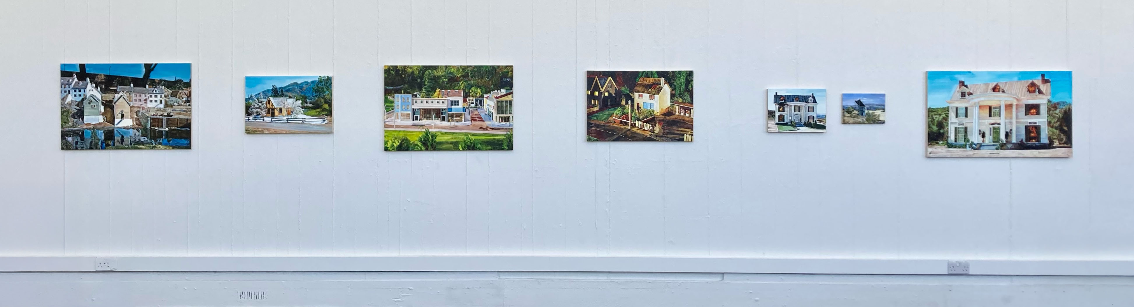 A long line of paintings on a white wall